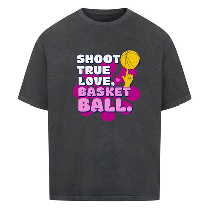 Washed Schwarz Oversized T-Shirt aus 100% Baumwolle mit einem pink-lila Retro-Print. Der Text lautet "SHOOT TRUE, LOVE, BASKETBALL" in Weiß mit dicken Rändern. Das Motiv zeigt einen Basketball und eine Hand.