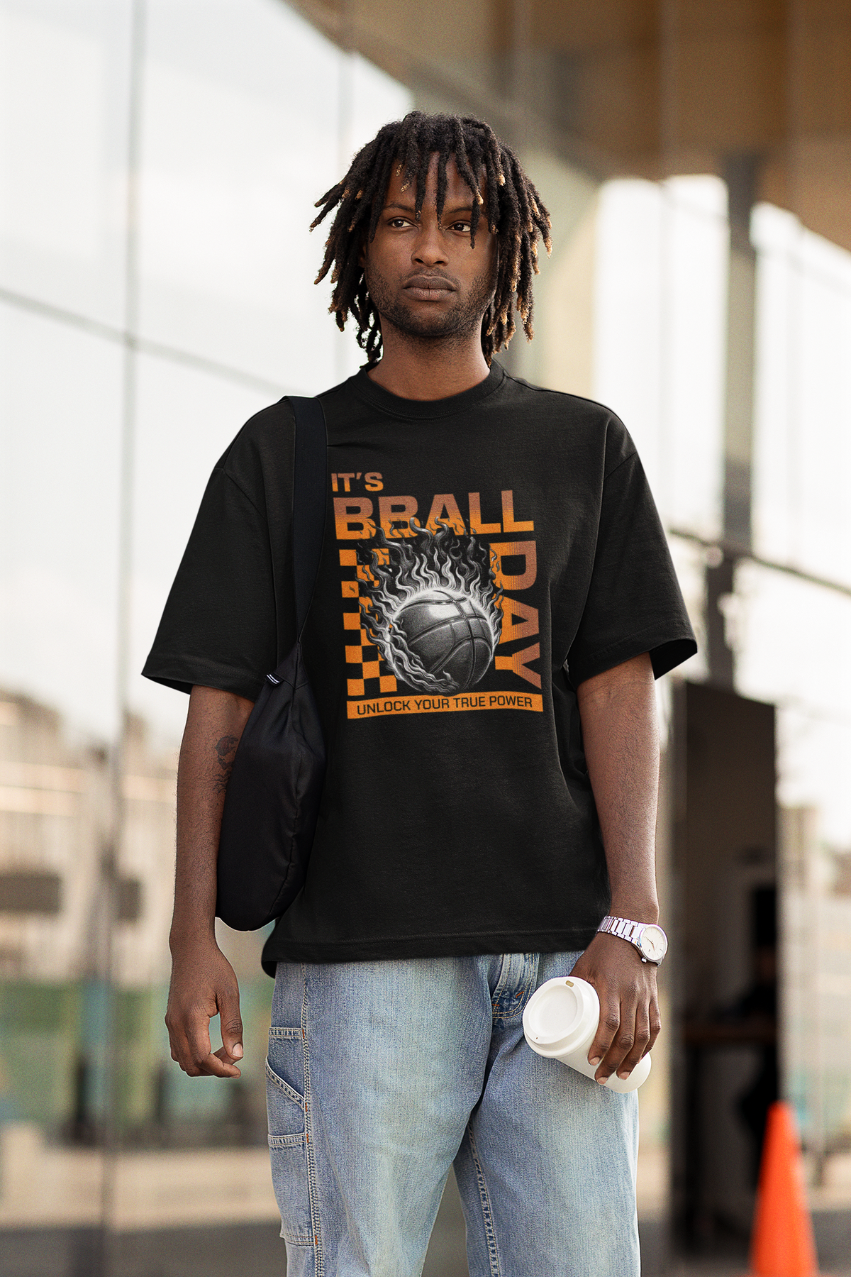Mockup mit Model Schwarzes Oversized T-Shirt mit einem Print eines brennenden Basketballs (Ball on Fire) und dem orangefarbenen Text „IT'S BBALL DAY“ und „UNLOCK YOUR TRUE POWER“. 100% Baumwolle.